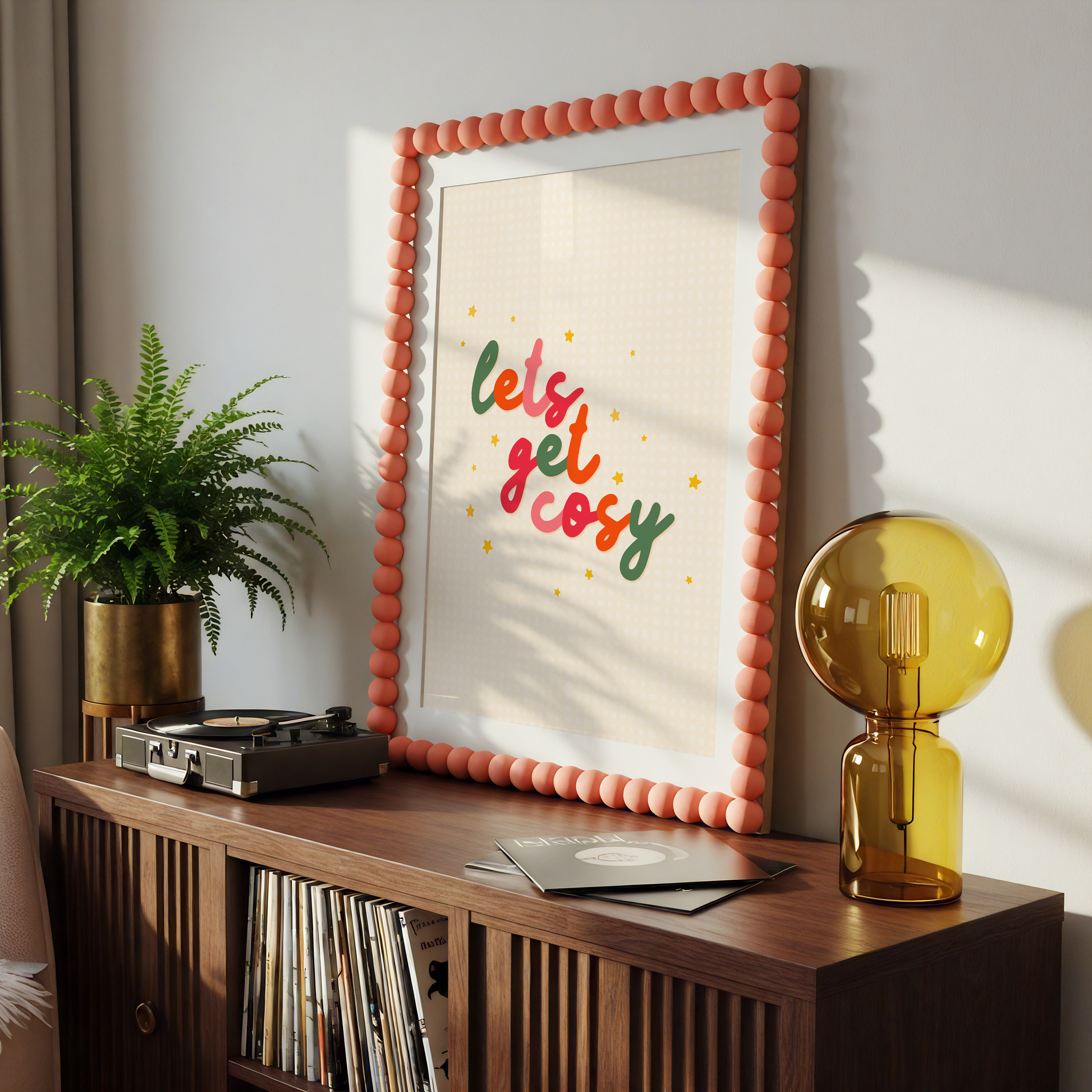 A quote print in autumnal colours that reads 'lets get cosy' in a handwritten font.
