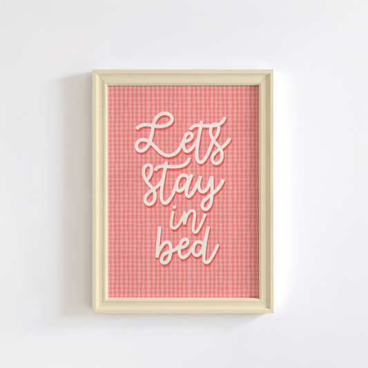 A pinky orange gingham print, with cursive handwriting that reads 'lets stay in bed' in cream.