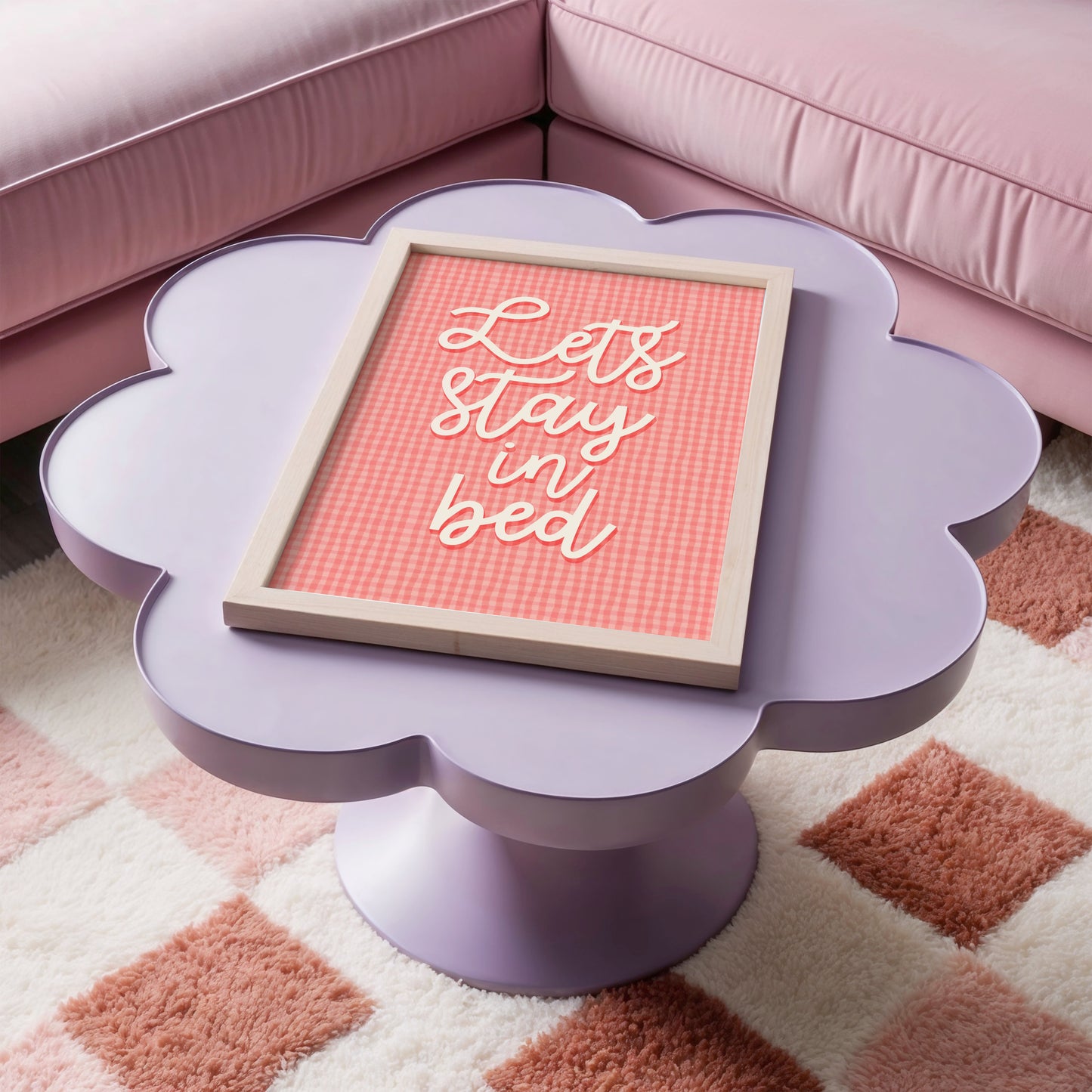A pinky orange gingham print, with cursive handwriting that reads 'lets stay in bed' in cream.