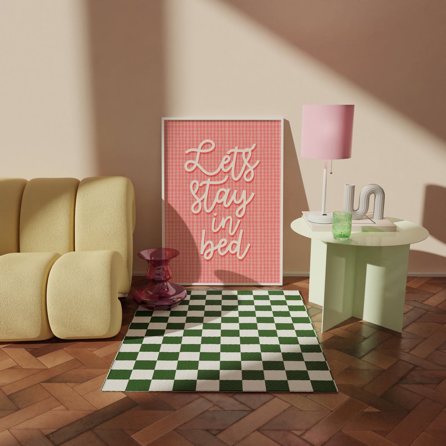 A pinky orange gingham print, with cursive handwriting that reads 'lets stay in bed' in cream.