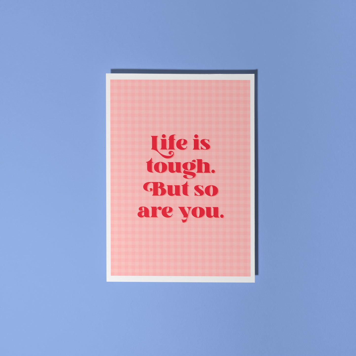 A pink and red card, that says 'life is tough but so are you.' on the front.