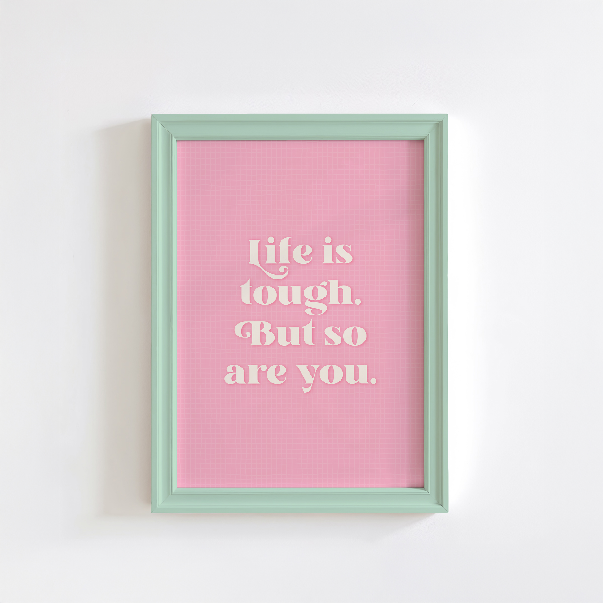 A pink print with a soft check pattern, and a quote in white that reads 'life is tough. But so are you.'.