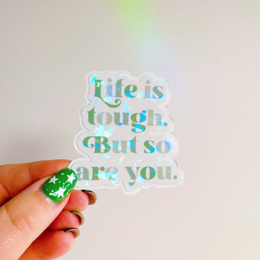 A holographic sticker, saying life is tough but so are you. The sticker has an easy peel lip.