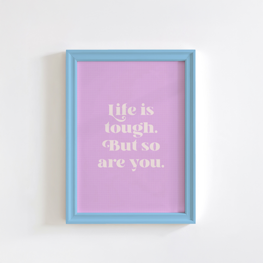 A framed print with a purple background and blue frame, containing the text 'Life is tough. But so are you.' in white font.