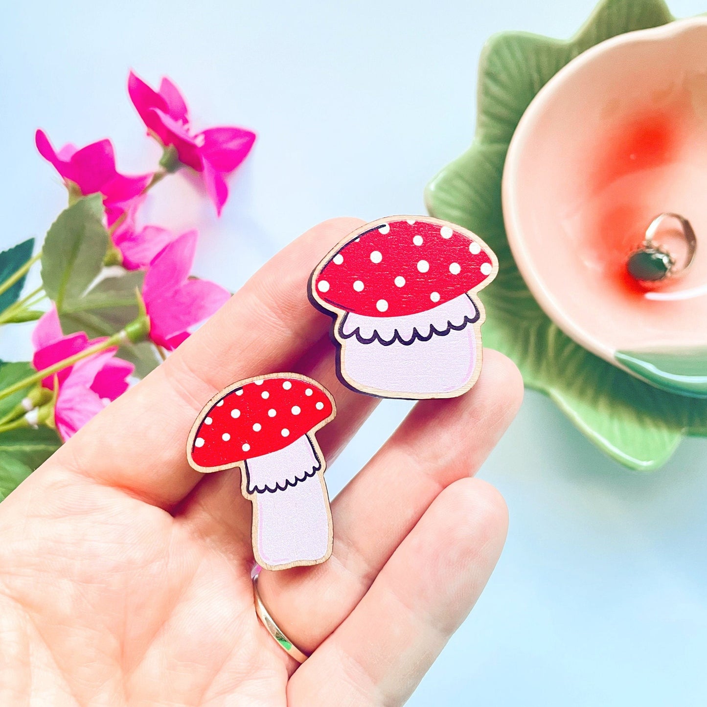 Two wooden eco friendly pin badges of a skinny and a chunky mushroom.