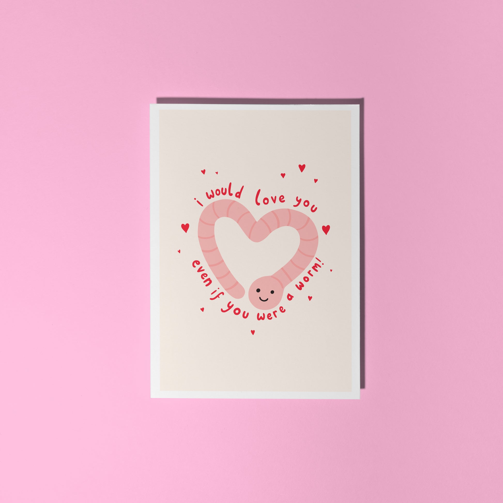An illustrated card with a drawing of a cute smiling worm on the front, in the shape of a heart. Around the worm is text that reads 'I would love you even if you were a worm!'.