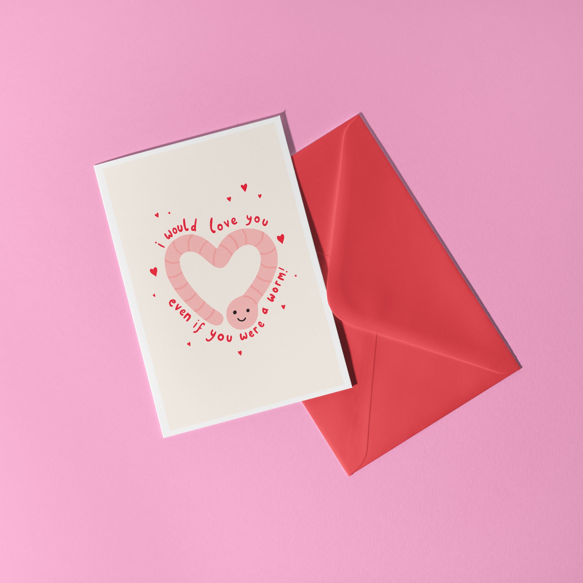 An illustrated card with a drawing of a cute smiling worm on the front, in the shape of a heart. Around the worm is text that reads 'I would love you even if you were a worm!'.