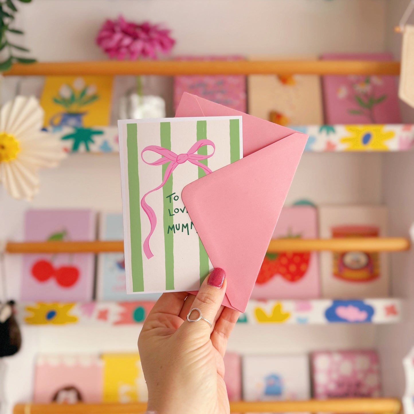A cream and green striped card, with a pink bow, and handwritten text that says 'to my lovely mummy'.