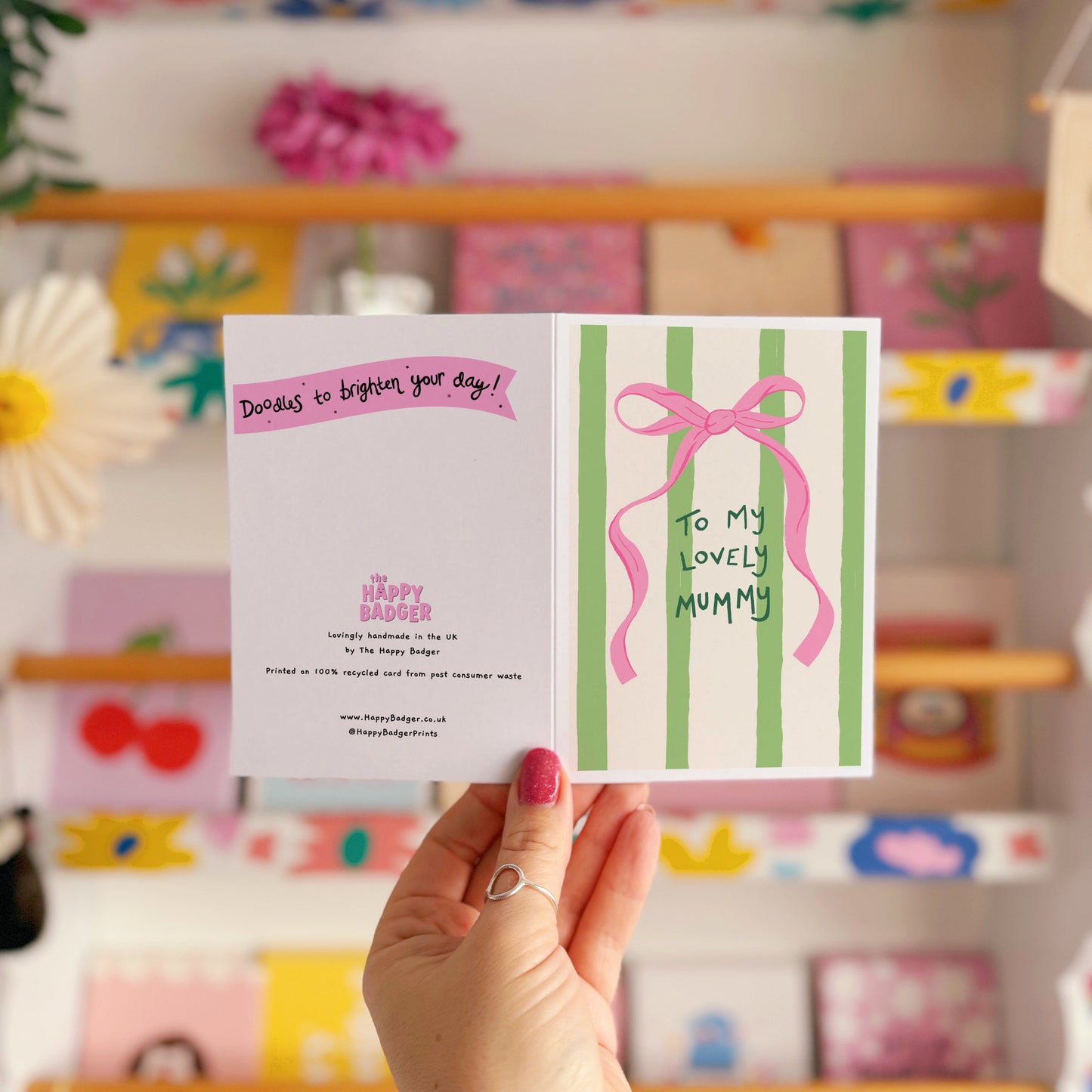 A cream and green striped card, with a pink bow, and handwritten text that says 'to my lovely mummy'.
