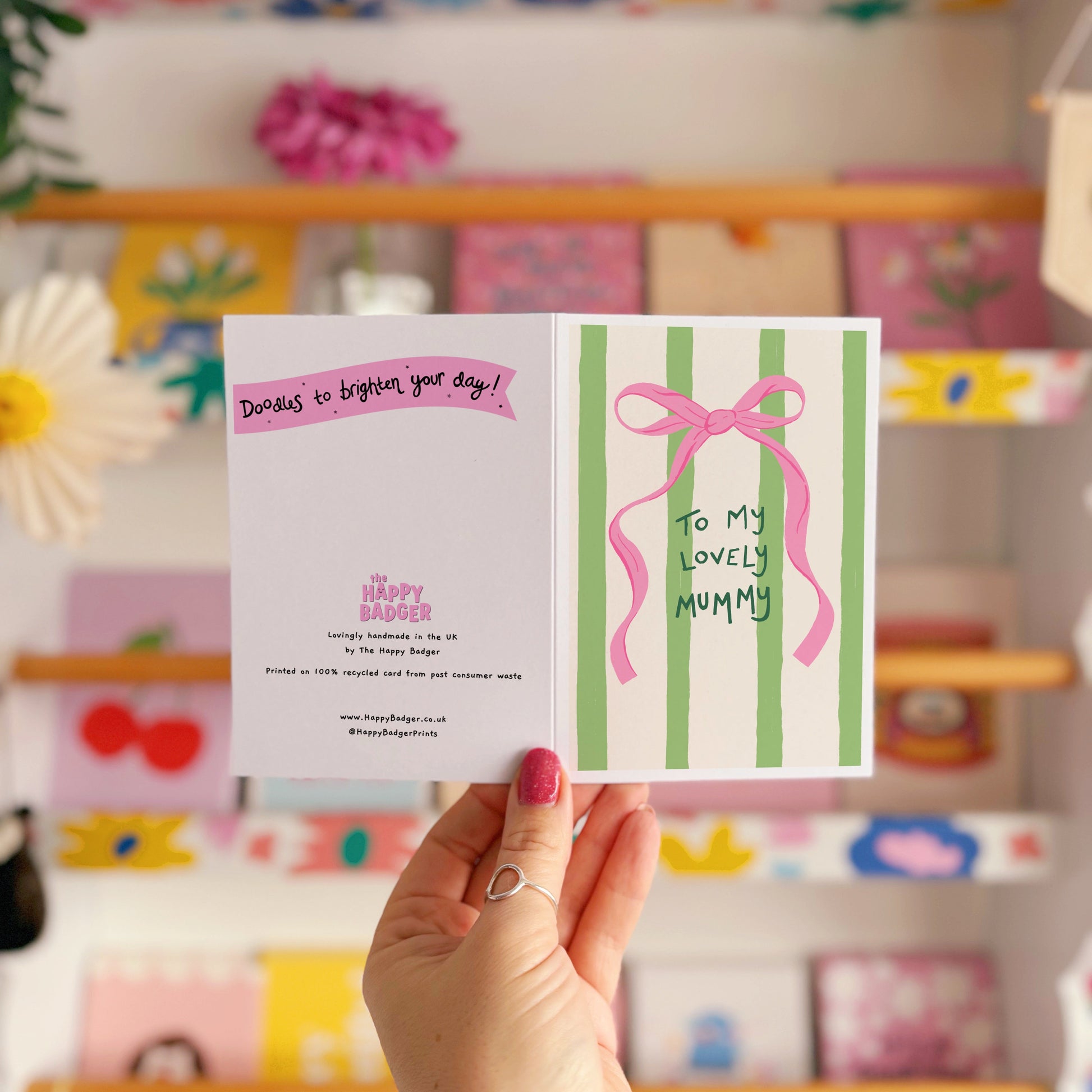A cream and green striped card, with a pink bow, and handwritten text that says 'to my lovely mummy'.