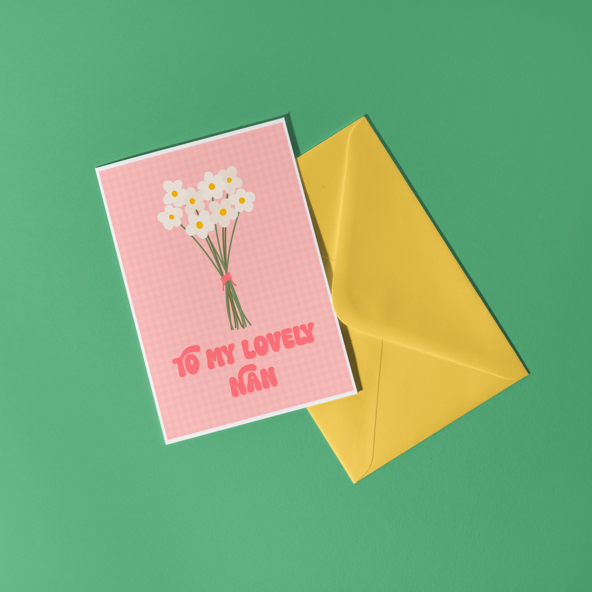 A pink greeting card with the words 'to my lovely nan' on the front, with a bunch of daisies.