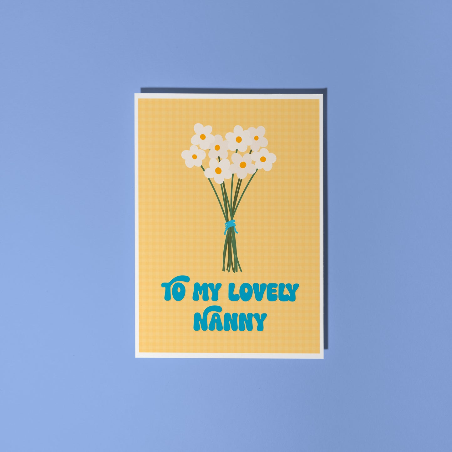 A yellow greeting card with the words 'to my lovely Nanny' on the front, with a bunch of daisies.