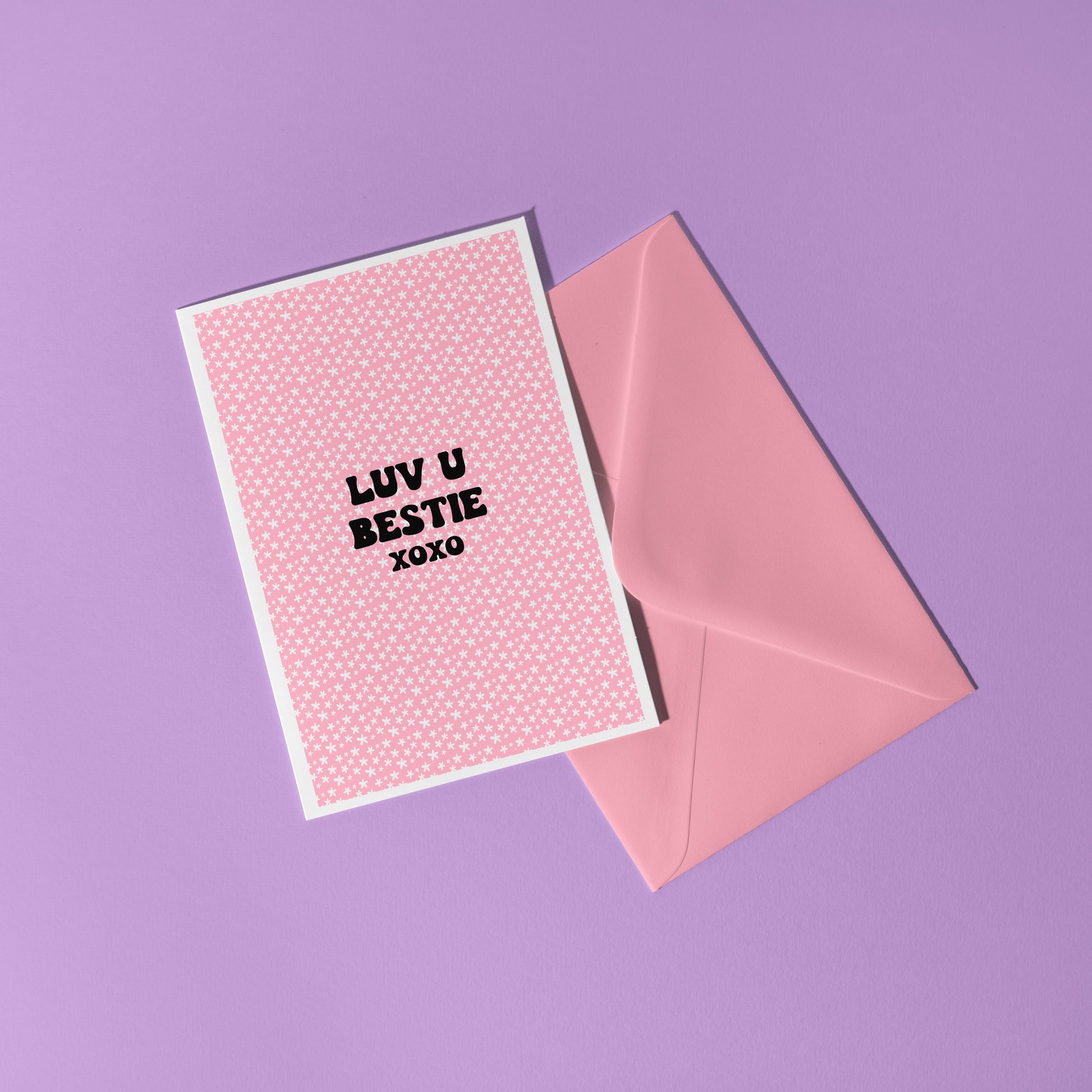 A pink card with little flowers all over, and black writing that says "Luv U Bestie xoxo".