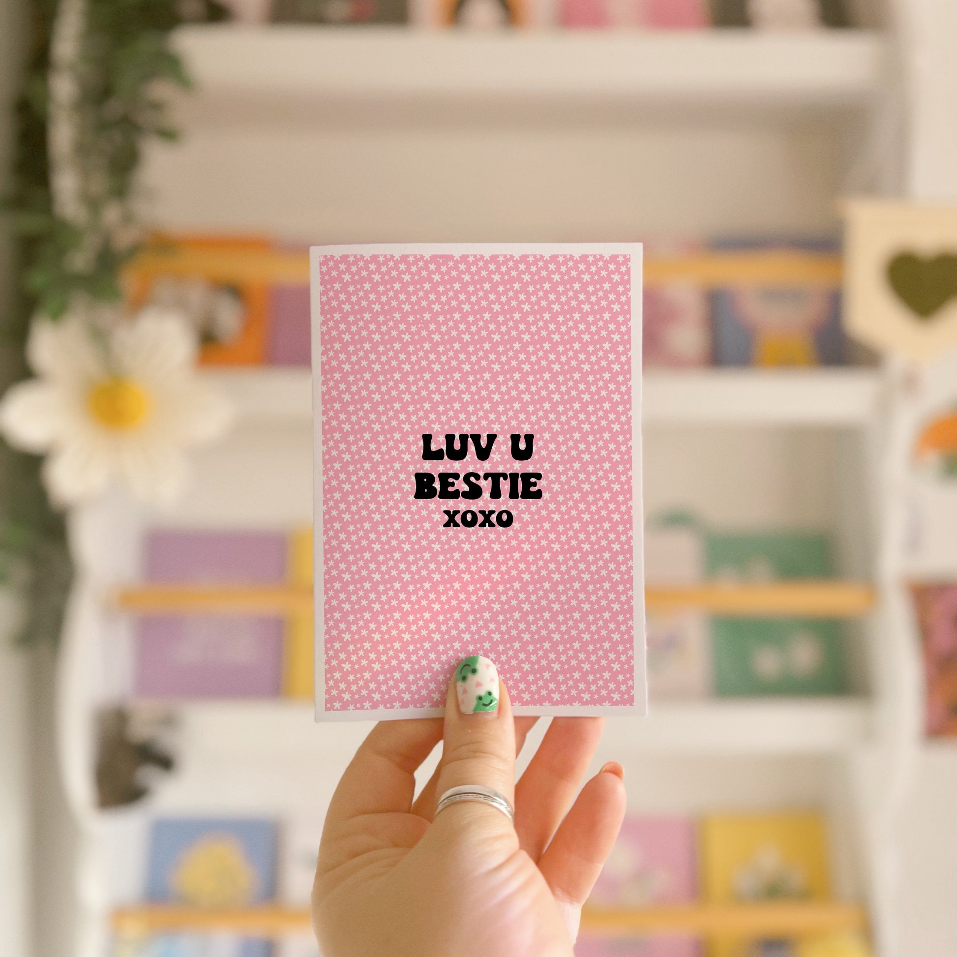 A pink card with little flowers all over, and black writing that says "Luv U Bestie xoxo".