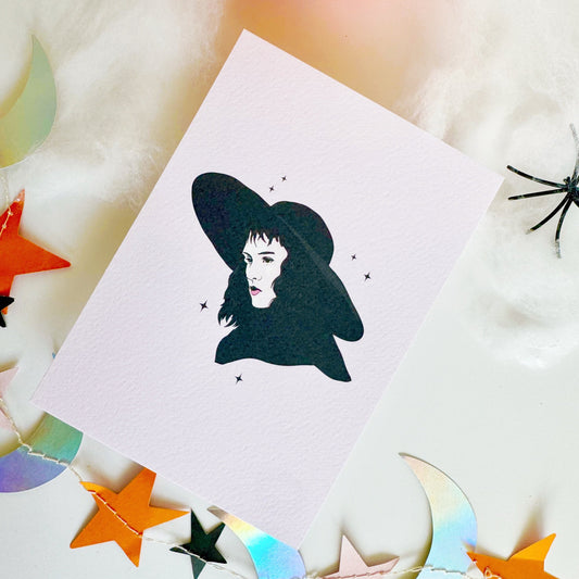 A halloween themed textured postcard with an illustration of Lydia Deetz, from Beetlejuice on the front.