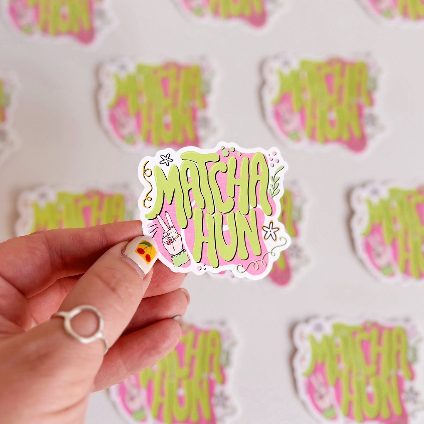 Hand holding a 'Match Hun' sticker with a matching background of similar stickers.