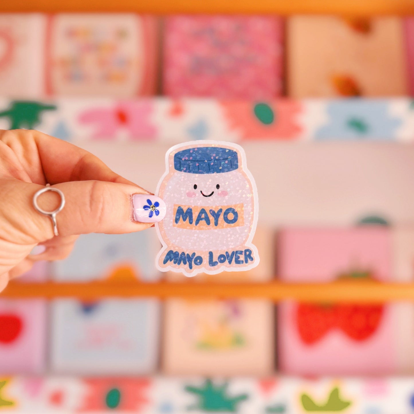 A holographic sticker, with an easy peel lip, featuring an illustration of a jar of mayonnaise. The words 'mayo lover' are underneath in blue.