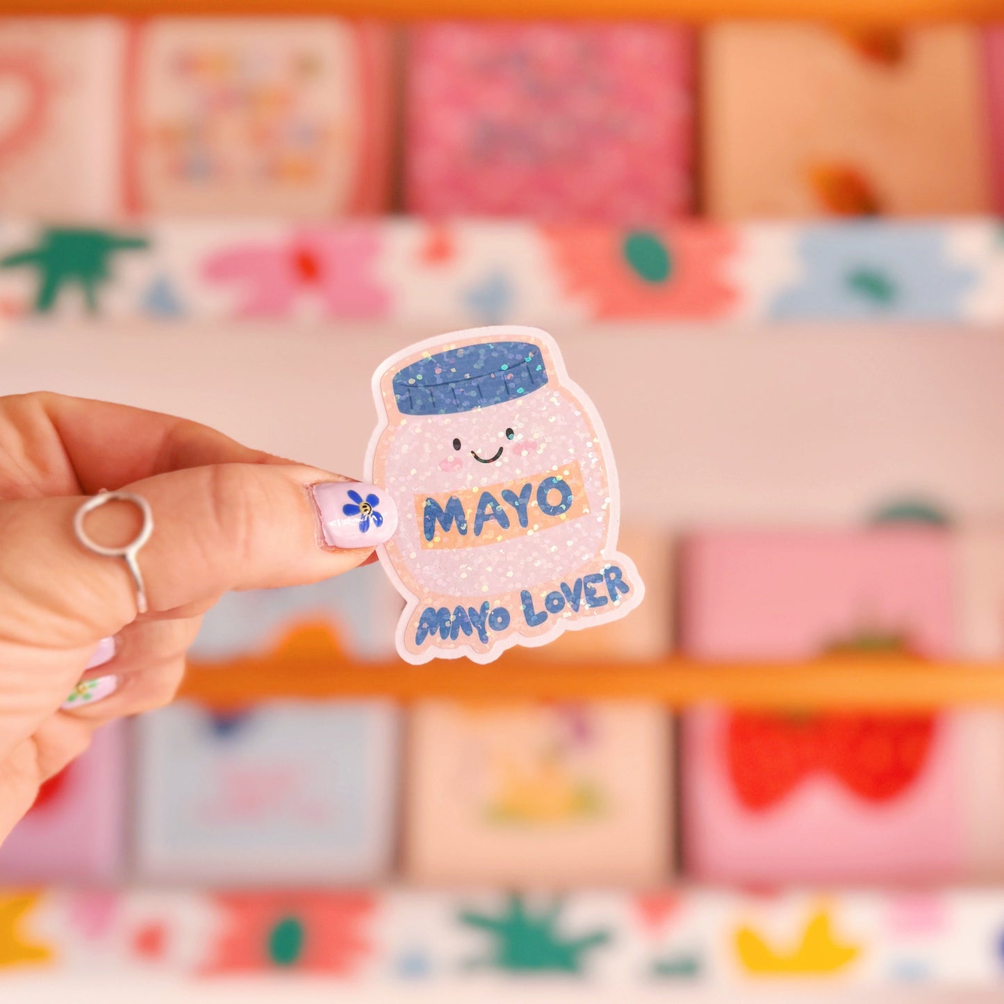 A holographic sticker, with an easy peel lip, featuring an illustration of a jar of mayonnaise. The words 'mayo lover' are underneath in blue.