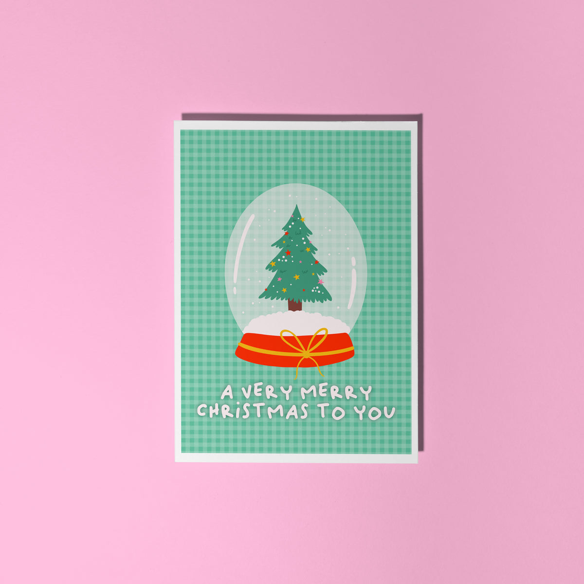 A green Christmas card with an illustration of a snow globe with a Christmas tree inside. The message on the front of the Christmas card reads 'A very Merry Christmas To you'