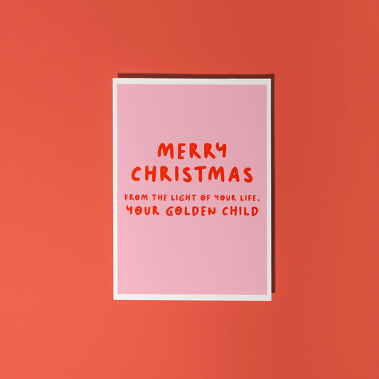 A pink Christmas card with text in off-white that reads 'Merry Christmas from the light of your life, your golden child.'