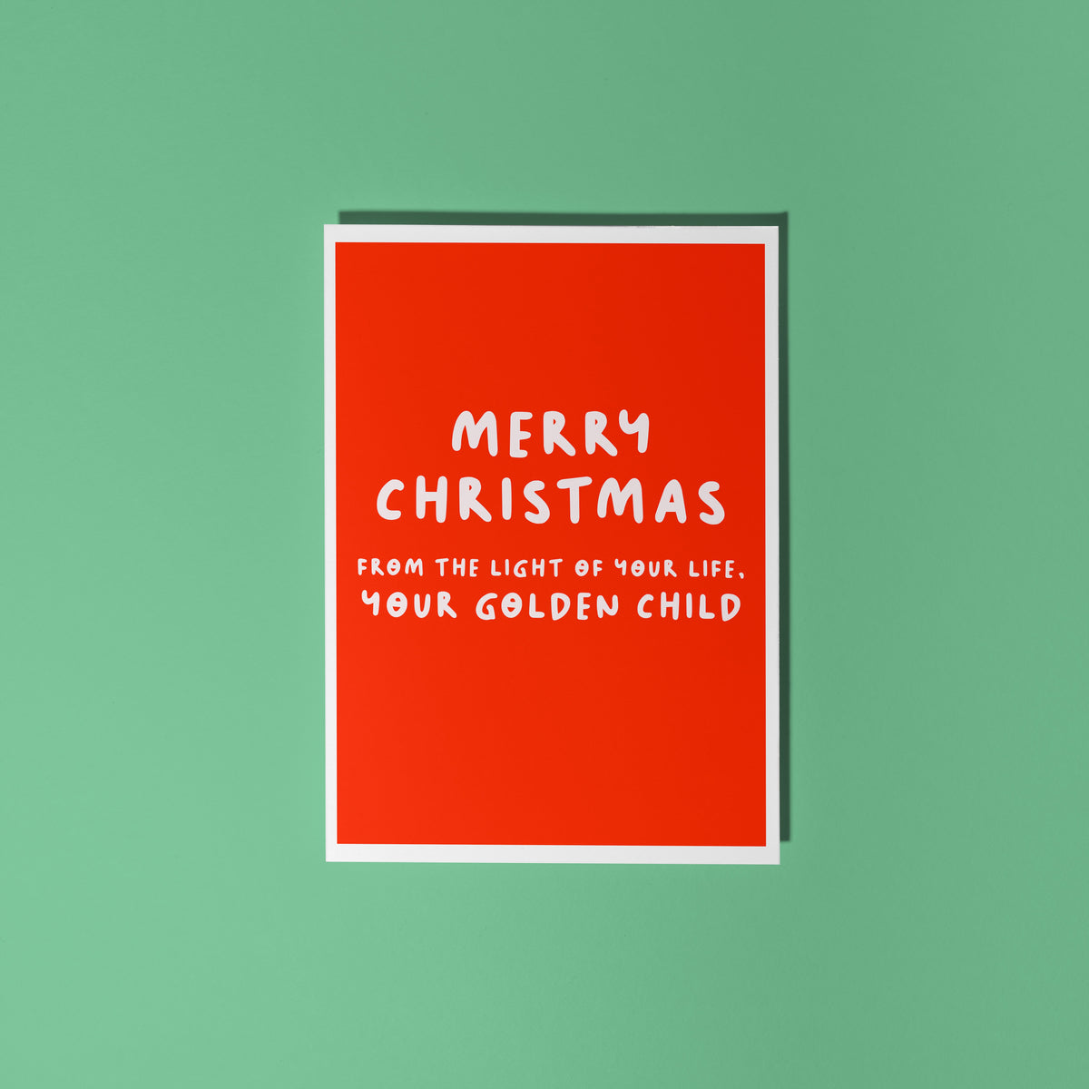 A red Christmas card with text in off-white that reads 'Merry Christmas from the light of your life, your golden child.'