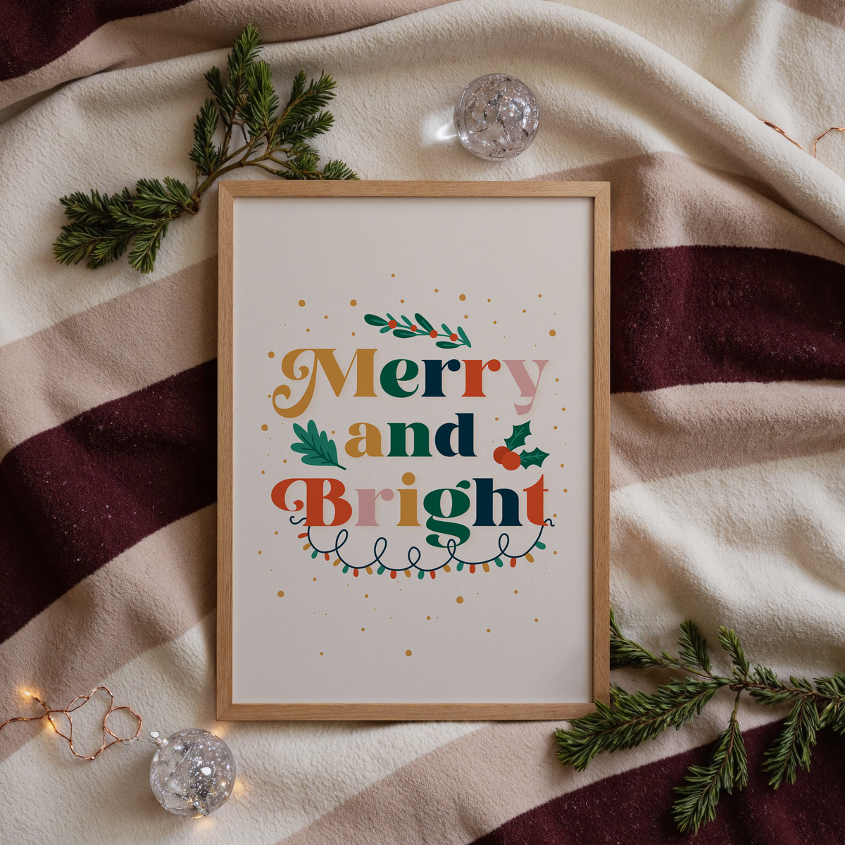 A festive quote print featuring the words 'merry and bright' in lots of traditional seasonal colours, surrounded by little festive doodles of Christmas lights and holly.