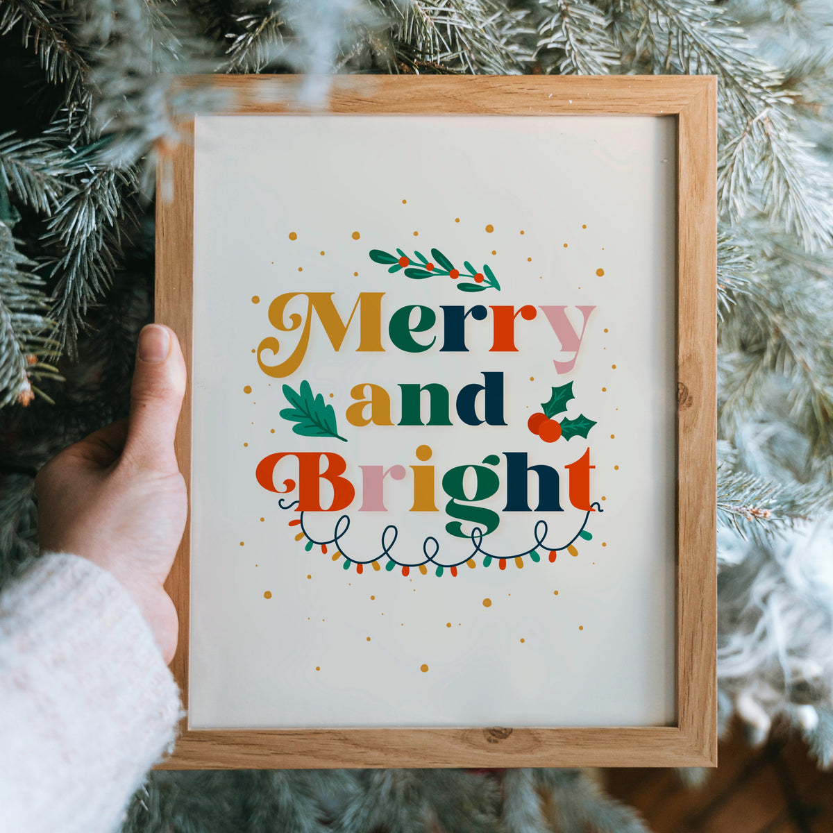 A festive quote print featuring the words 'merry and bright' in lots of traditional seasonal colours, surrounded by little festive doodles of Christmas lights and holly.