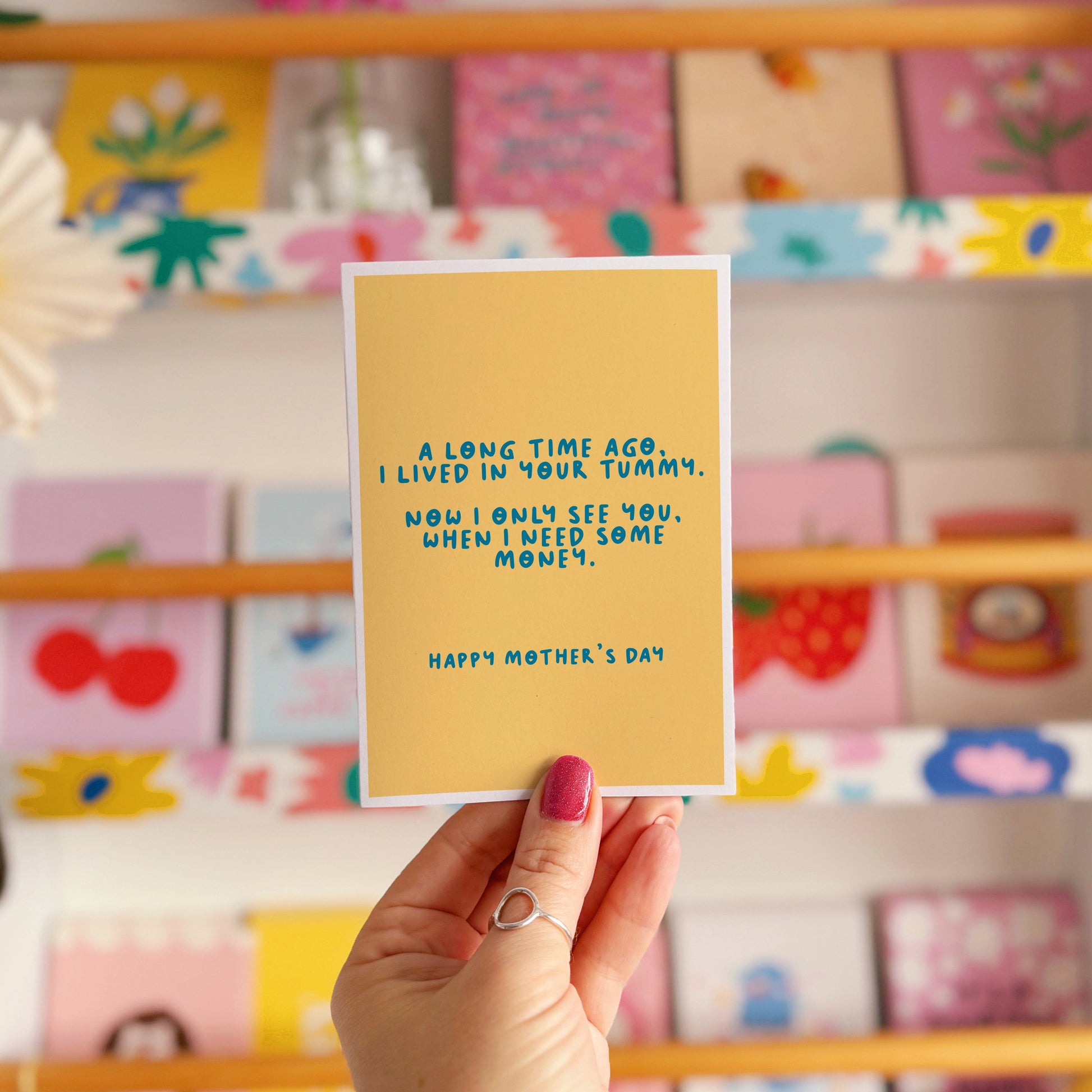 A yellow Mother's Day card with a funny quote, that says 'A long time ago I lived in your tummy. Now I only see you, when I need some money. Happy Mother's Day".