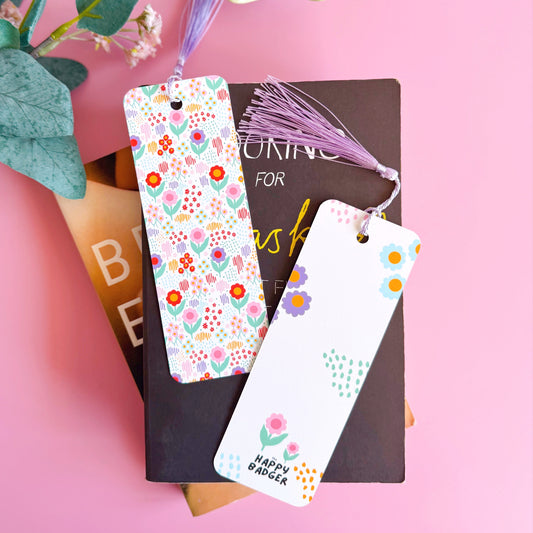 A multi coloured floral bookmark, with a coordinating lilac purple tassel. The pattern is on a white background and features pink, green, purple and red across the flower pattern.