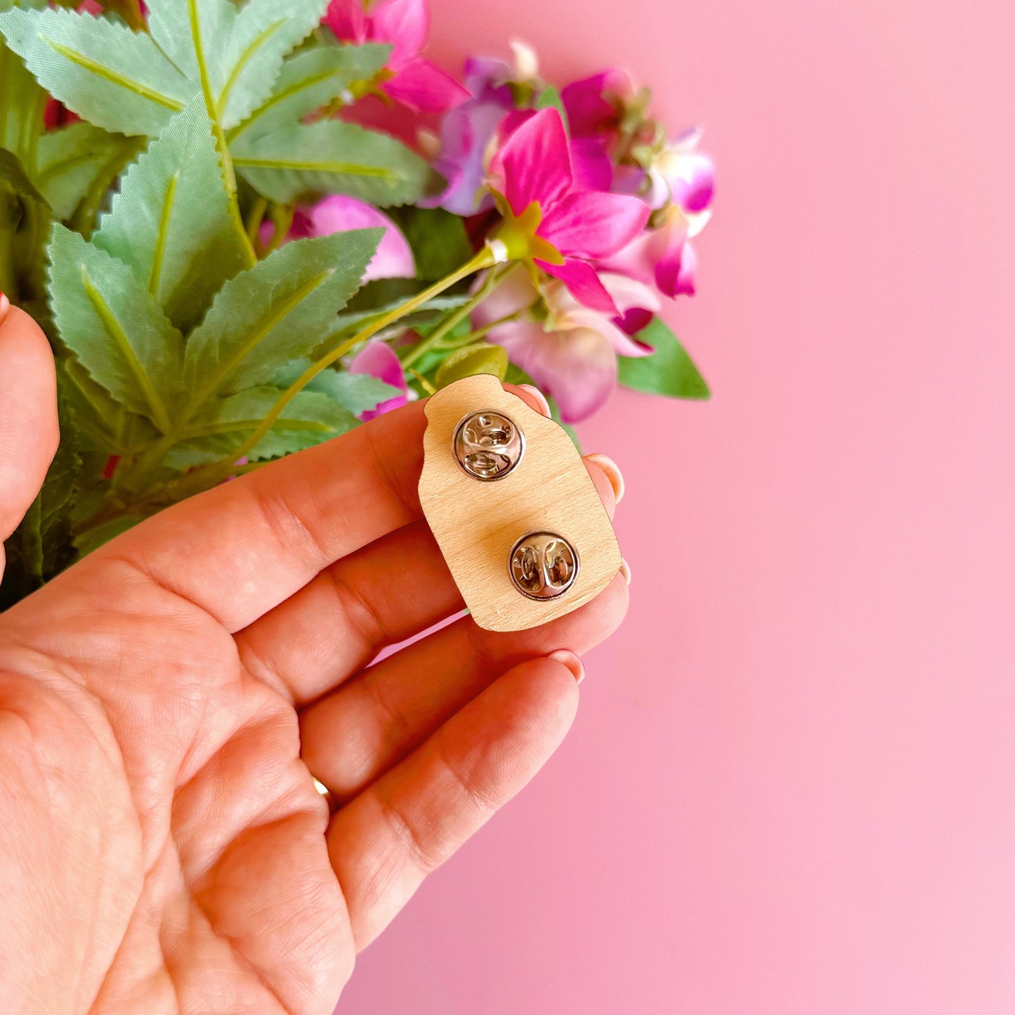 A wooden pin badge featuring an illustration of a terrarium filled with mushrooms and woodland elements.