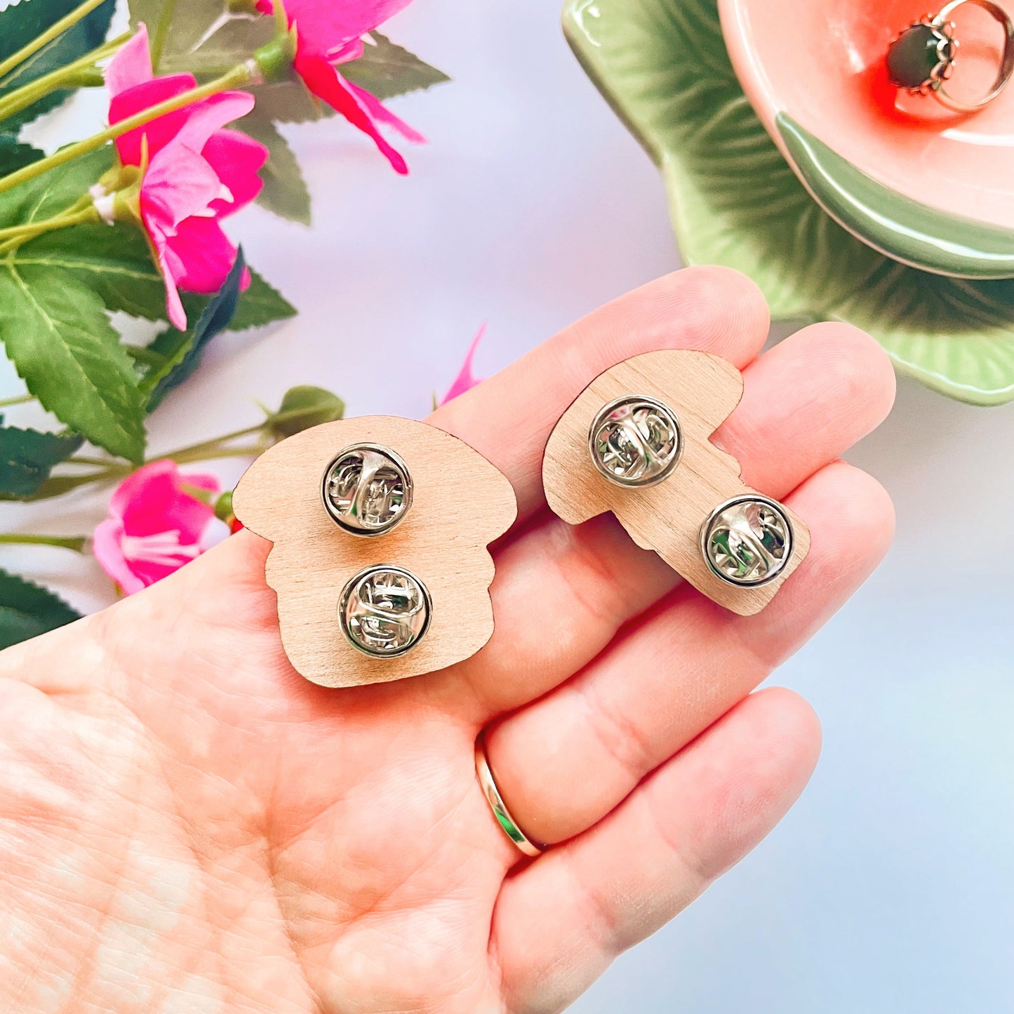 The backs of two wooden eco friendly pin badges of a skinny and a chunky mushroom.