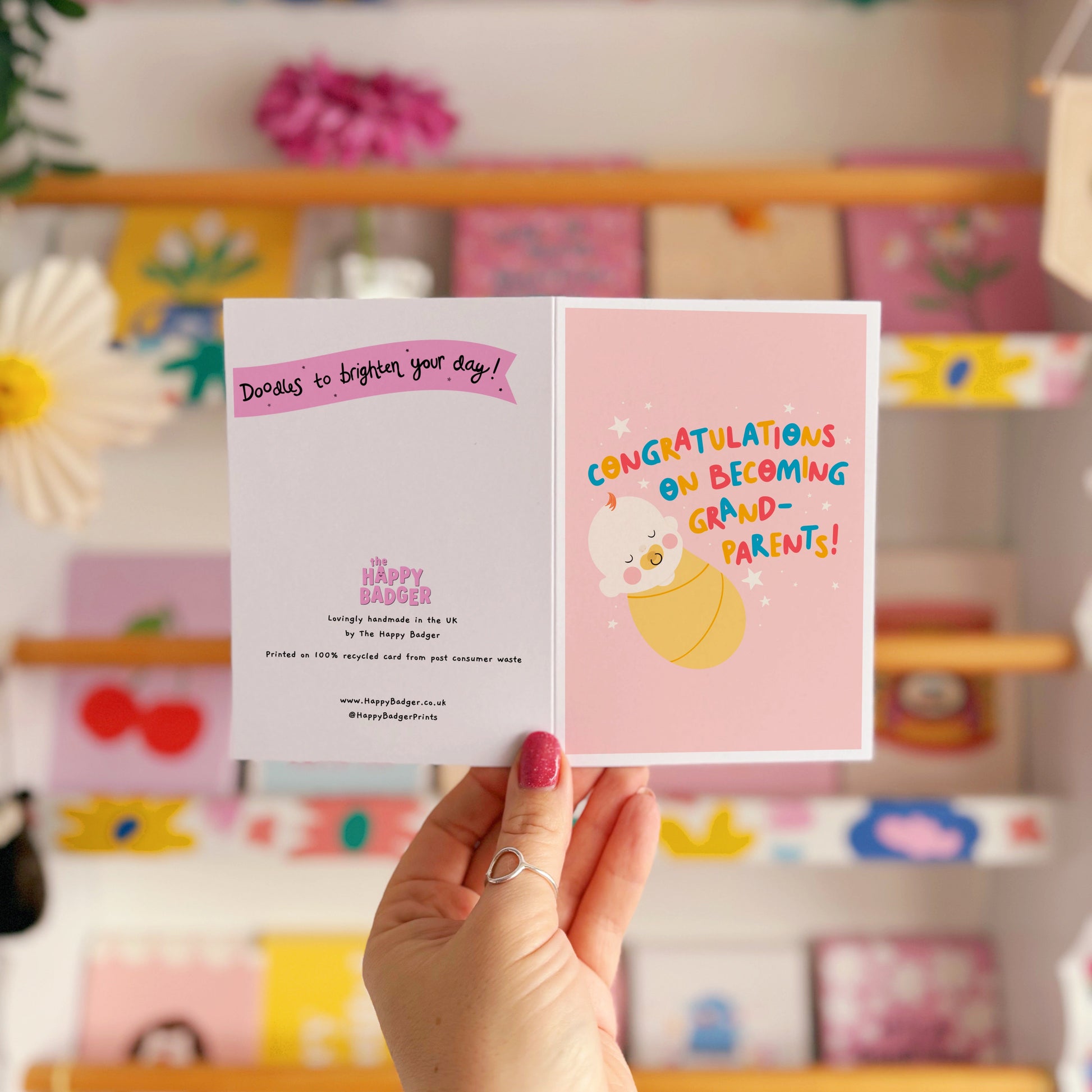 A card for congratulating new grandparents on the arrival of their new grandchild, with an illustration of a baby and colourful text.