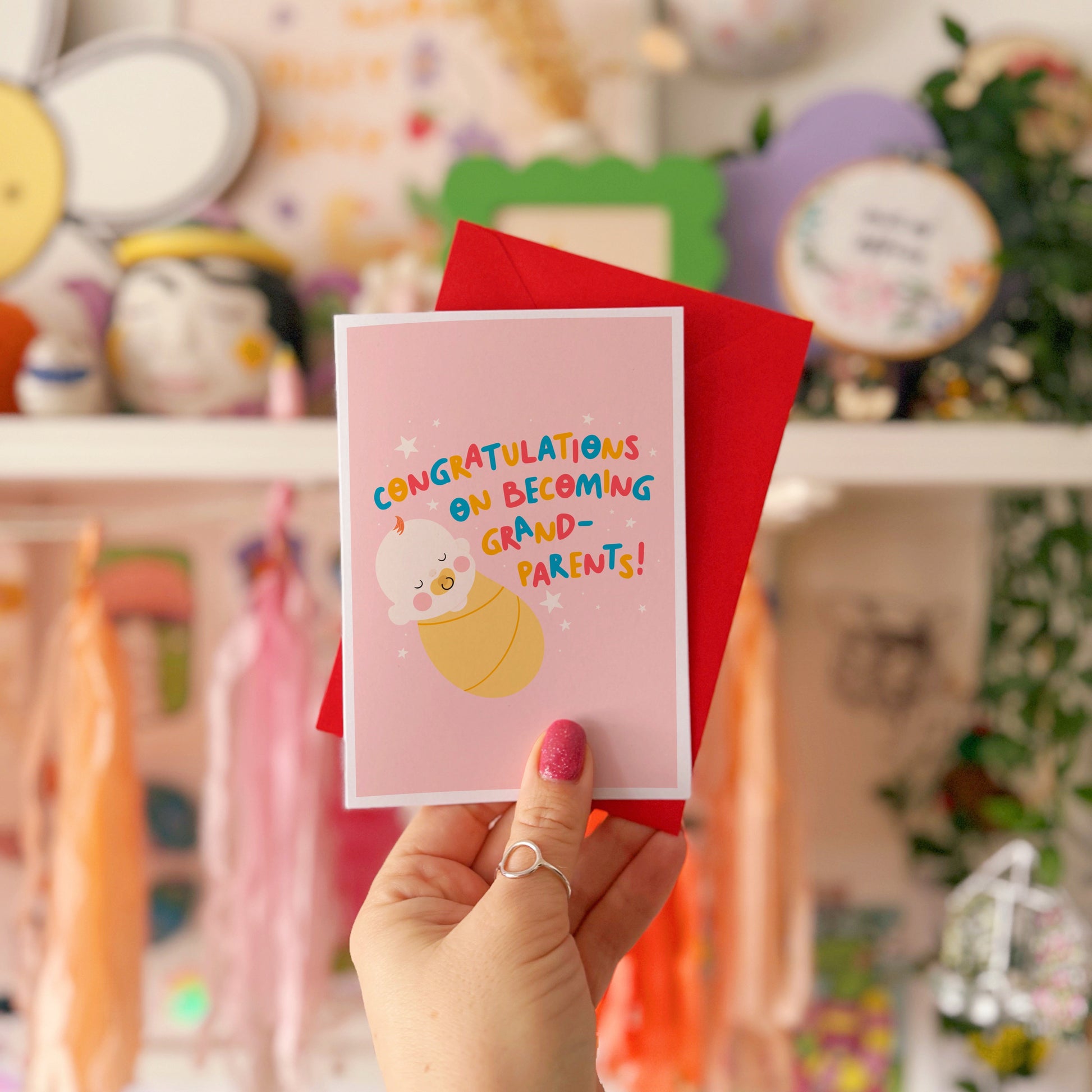 A card for congratulating new grandparents on the arrival of their new grandchild, with an illustration of a baby and colourful text.