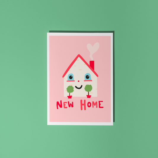 A new home congratulations card with an illustration of a little house with a smiling face and hand lettering underneath that reads 'New Home'.