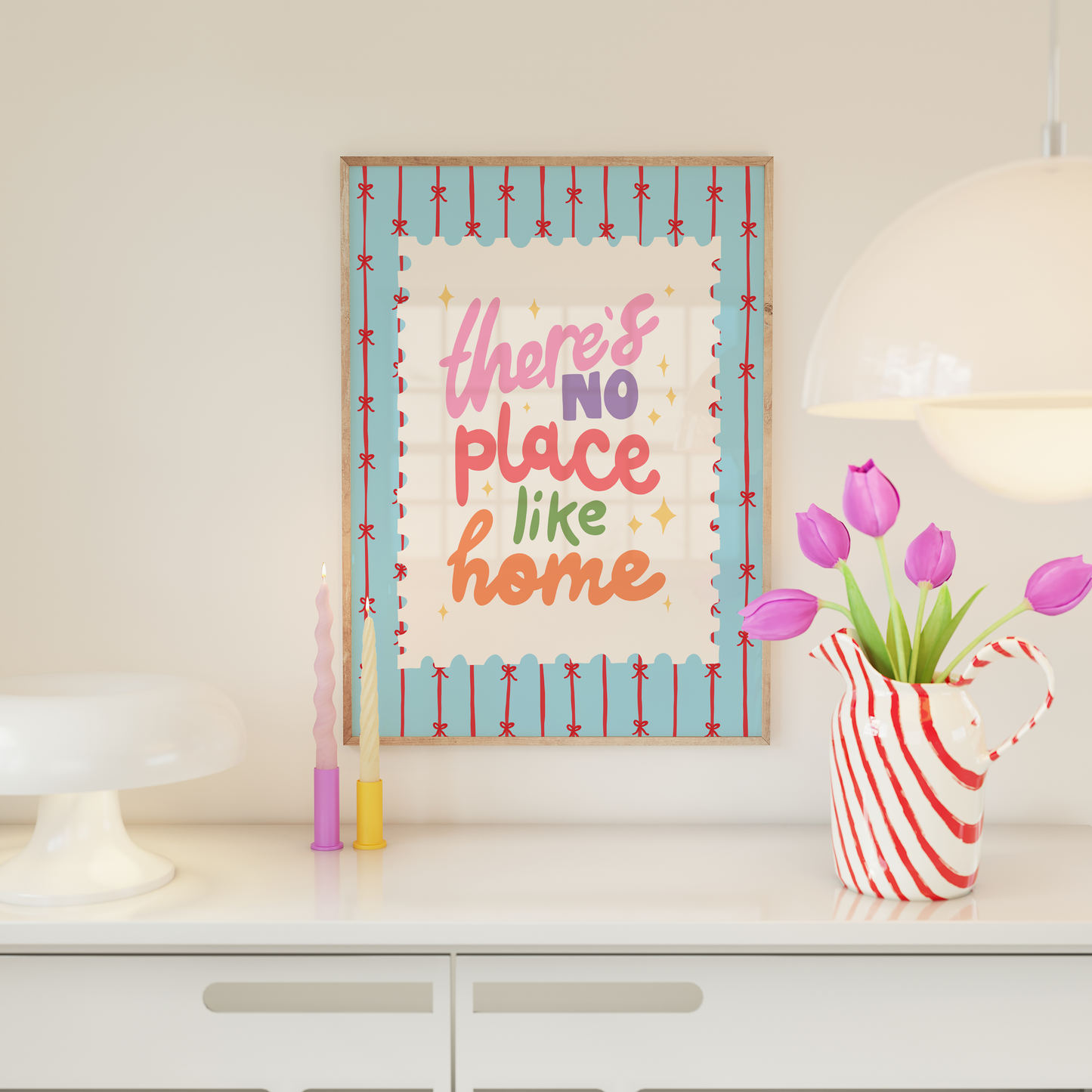 A blue print with red stripes and bows across it, in the centre is a postage-stamp style border with hand lettered text that reads 'there's no place like home'.