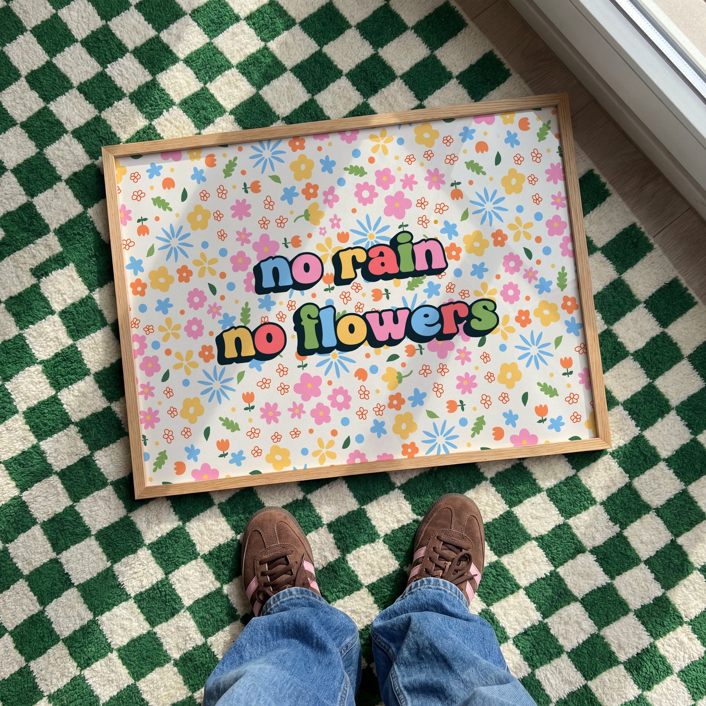 A colourful floral patterned print, with bright multi coloured text that reads 'no rain no flowers' in the centre.