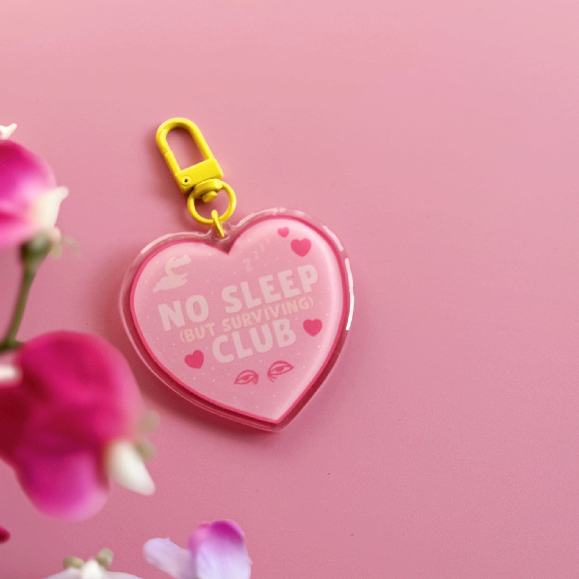 Heart-shaped keychain with 'No Sleep But Surviving Club' on, with a yellow clasp.