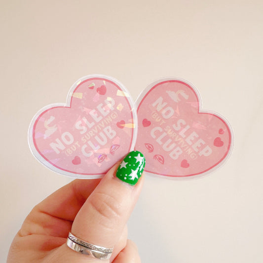 A holographic sticker, a pink heart with the words 'no sleep but surviving club' in. The sticker has an easy peel lip.