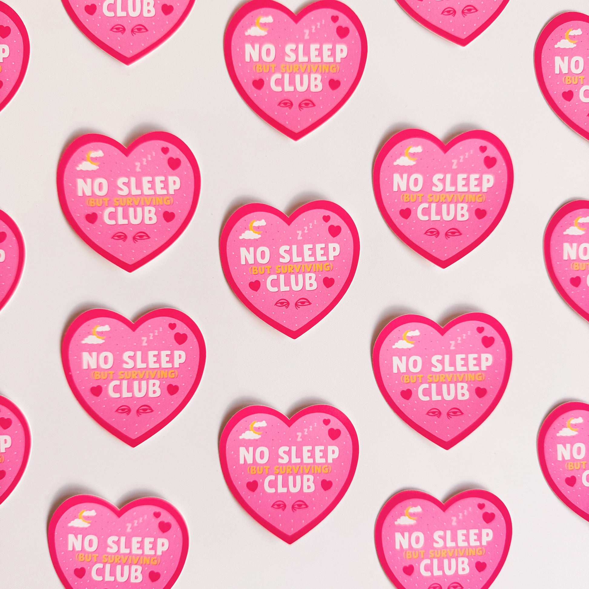 A pink heart-shaped sticker with a 'No Sleep Club' quote and little illustrations relating to sleep and tiredness.