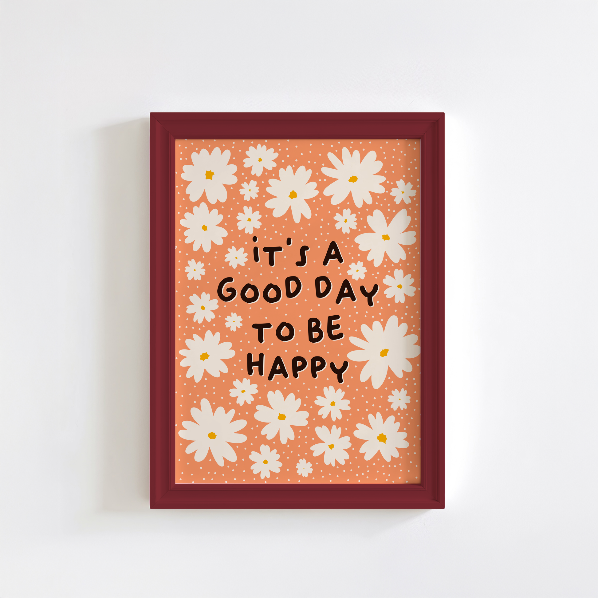 Framed artwork with white flowers and 'it's a good day to be happy' text on an orange background.