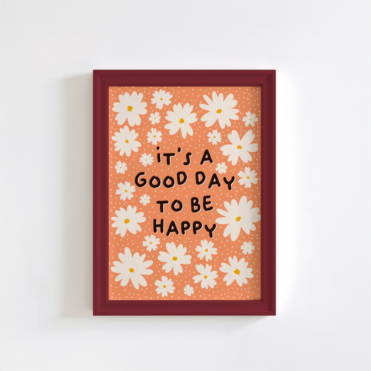 Framed artwork with white flowers and 'it's a good day to be happy' text on an orange background.