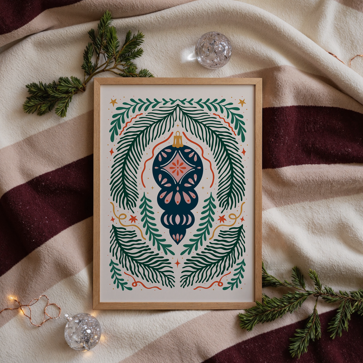 A detailed Christmas illustration print, featuring a traditional style Christmas bauble in the centre of the page with a symmetrical design or fir, ribbons and stars around it.