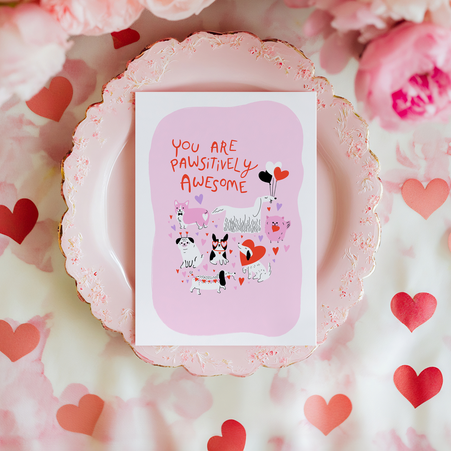 A greetings card for love and appreciation, showing 7 quirky dog illustrations surrounded by hearts and love themed elements. The text on the card is red and says 'You are pawsitively awesome'