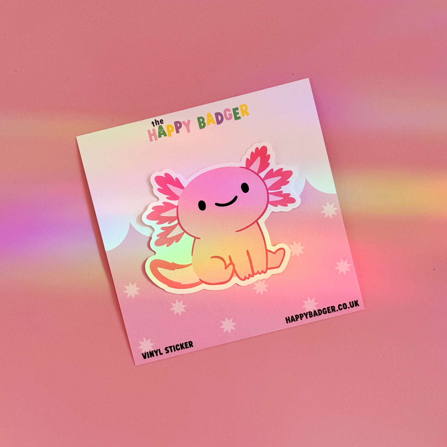 A waterproof vinyl sticker featuring an illustration of a cute pink smiling axolotl. 