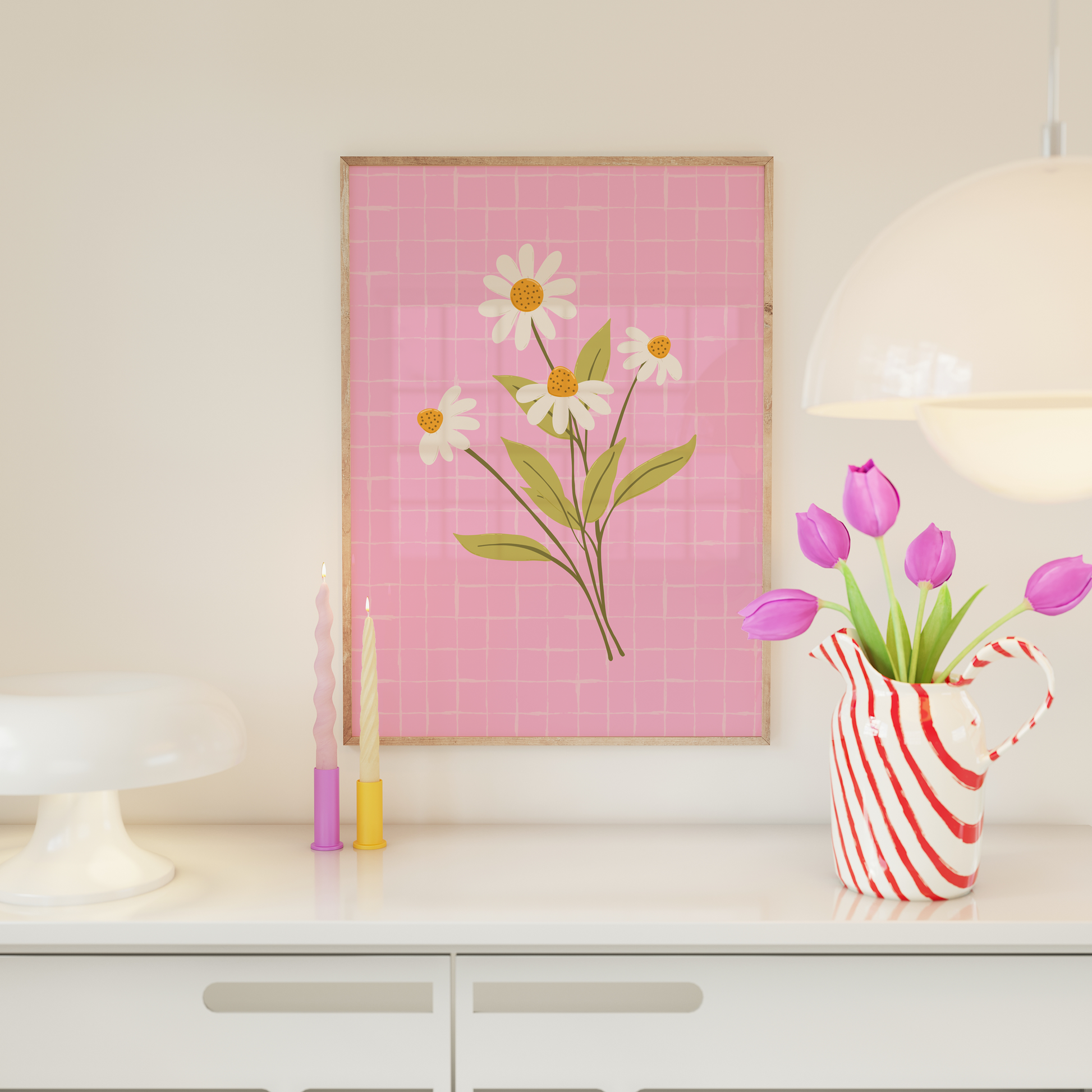 Decorative wall art with flowers on a pink grid background, placed on a shelf with a vase and candles.