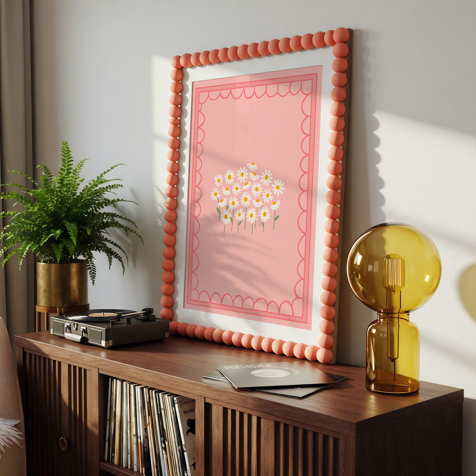 A pink print with an illustration of a bunch of white daisies on, with a scalloped pink border.