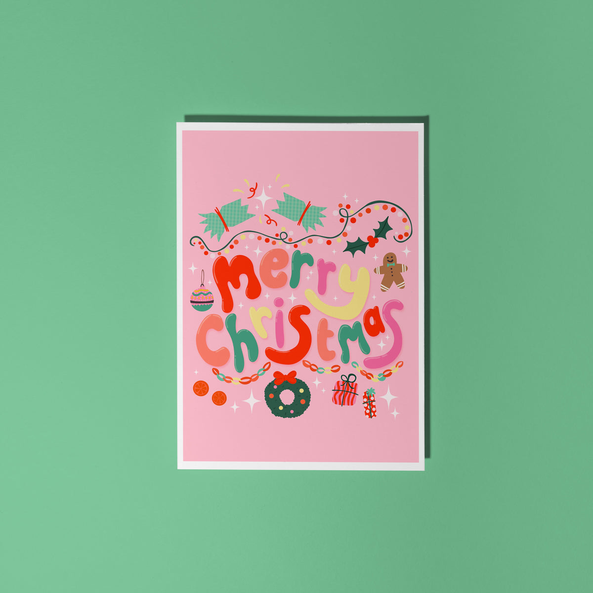 A bright pink Christmas greeting card with colourful retro-style lettering and festive illustrations.