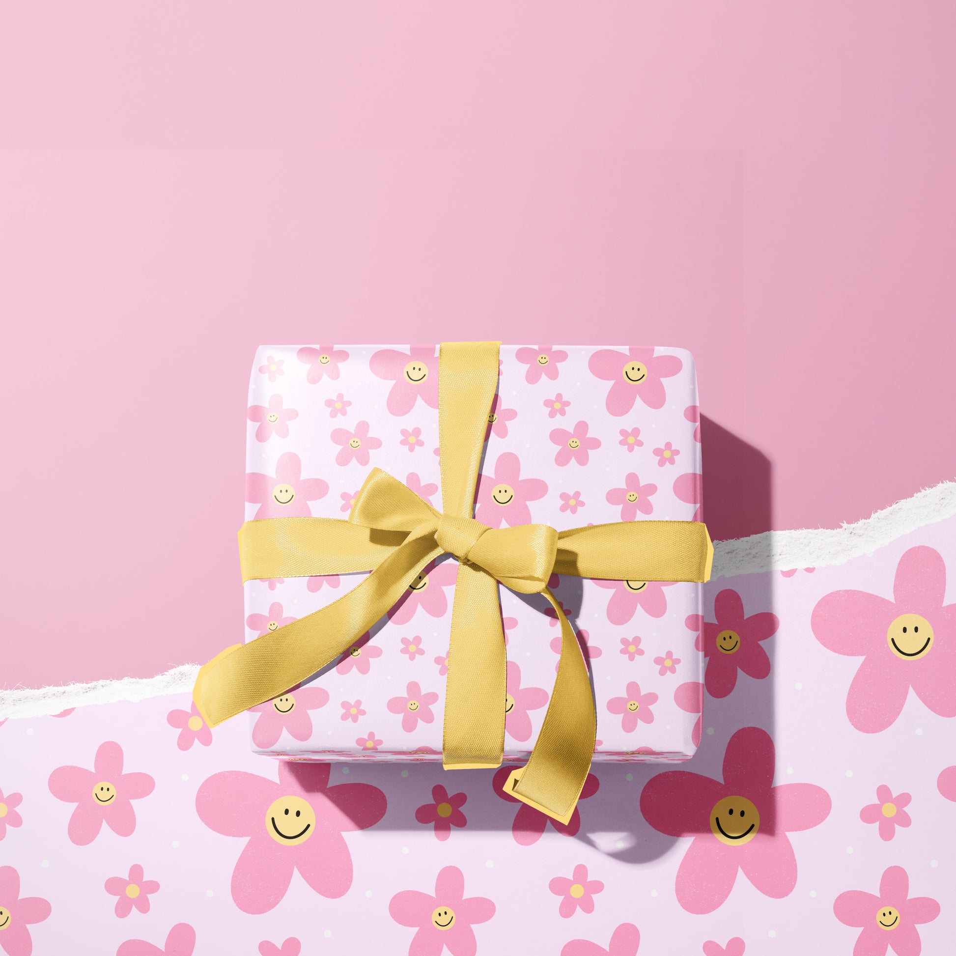 A present wrapped in a sheet of pink gift wrap with pink smiling daisies all over it.
