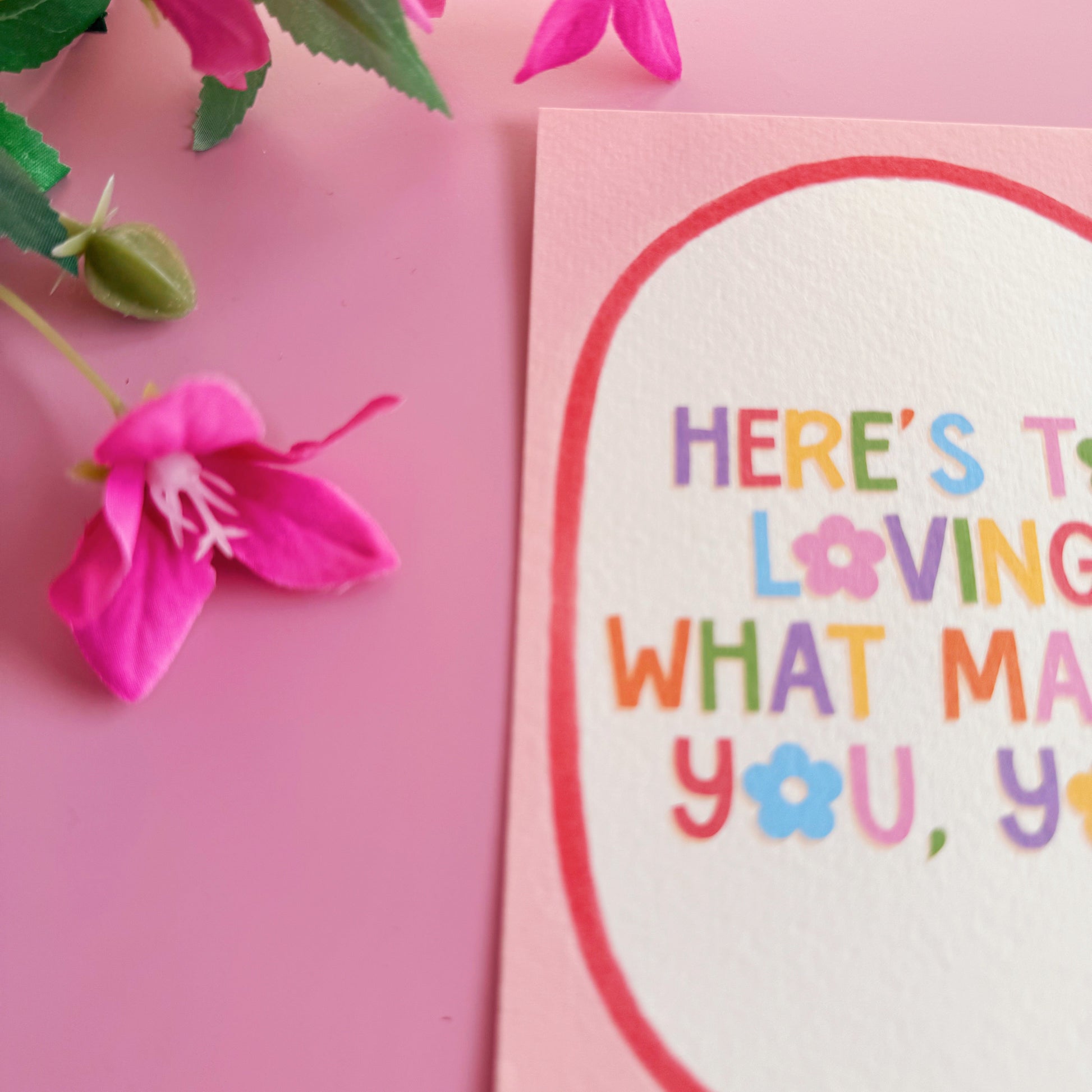 A pink postcard with a colourful positive quote on. 