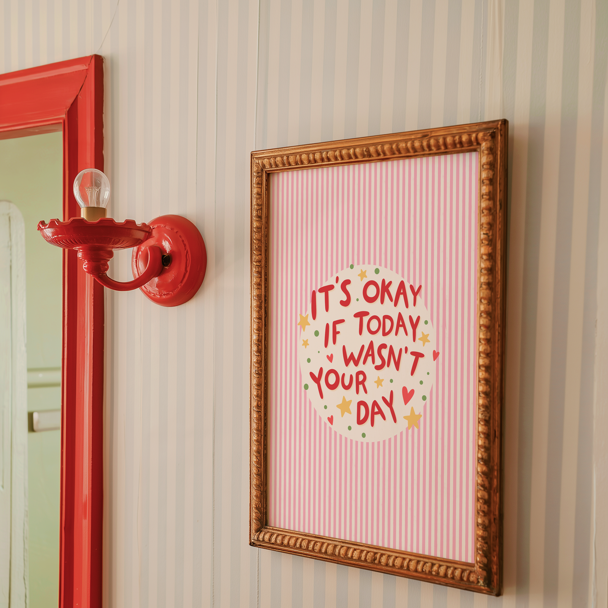 A red striped artwork, shown in a frame, with a motivational quote in the centre, decorated with stars and hearts.